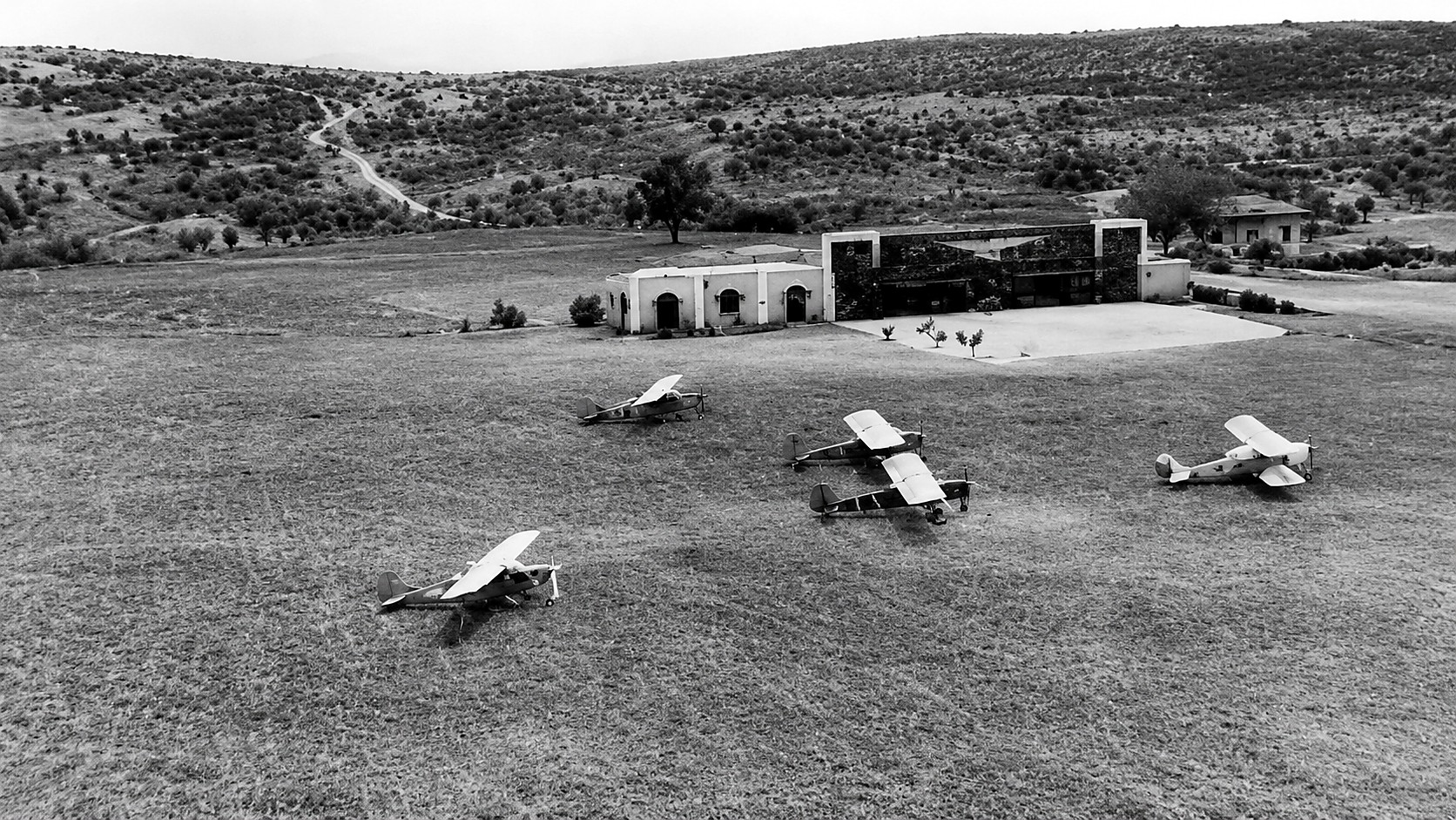 Fotografia histórica do campo do Aero Clube de Angola com várias aeronaves estacionadas em frente às instalações